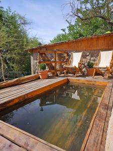 a swimming pool with two chairs and a wooden deck at Anka Lodge Quitor in San Pedro de Atacama