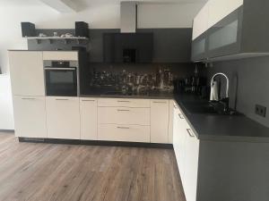 cocina con armarios blancos y encimera negra en Ferienwohnung Haus Waldesruh, en Olsberg