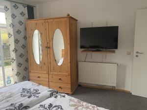 a bedroom with a tv and a wooden cabinet with two mirrors at Ferienwohnung Haus Waldesruh in Olsberg