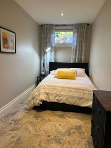 a bedroom with a bed with a yellow pillow on it at Farmhouse Apartment Guelph Elora in Guelph