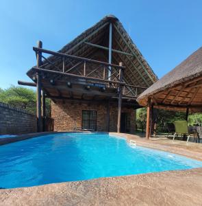 a large swimming pool with a thatched roof at Giraffe plains in Marloth Park