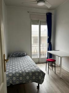 a bedroom with a bed and a table and a window at Habitaciónes Luminosas y acogedoras in Madrid