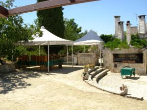 a patio with two white umbrellas and a fireplace at Trullo Malvisco in Alberobello