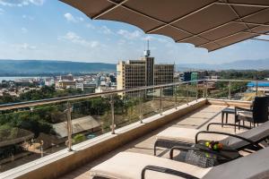 balcone con tavoli, sedie e vista sulla città di Acacia Premier Hotel a Kisumu
