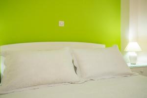 uma cama com almofadas brancas e uma parede verde em Aspasia Studios em Lixouri