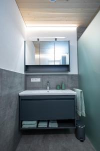 La salle de bains est pourvue d'un lavabo et d'un miroir. dans l'établissement Ferienwohnung Himmelmoos, à Au im Bregenzerwald