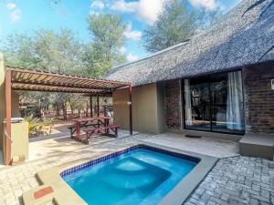 a swimming pool in front of a house with a picnic table at Athule Marloth in Marloth Park