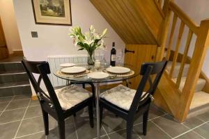 a dining room table with two chairs and a vase with flowers at Oaklands Cottage on a rural farm in Dingestow