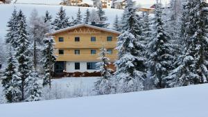 una casa nella neve con alberi innevati di Appartementhaus Bergkristall a Kartitsch