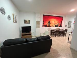 sala de estar con sofá negro y mesa en Malaguetor Home, en Málaga
