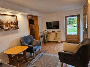 a living room with two chairs and a table and a tv at Apartamenty Cicha Dolina in Jurgów