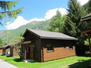 ein Blockhaus mit einem Berg im Hintergrund in der Unterkunft Residenz Edelweiss SAAS321 - b47720 in Saas-Balen