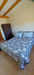 een bed met een blauw en wit dekbed in een kamer bij Cabañas Lya in Puyehue