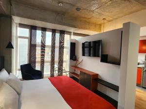a bedroom with a bed and a desk and a television at Hotel 5 Elementos Corferias by HBP in Bogotá