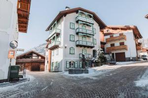 un gran edificio blanco con ventanas verdes en una calle en Il Rifugio di Dante - 10 Minuti dagli Impianti, Deposito e Parcheggio Privato en Moena