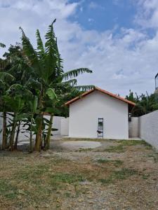 un bâtiment blanc avec un banc à côté des arbres dans l'établissement Recanto Ganesha seu paraíso na praia, no Recanto de Itaipuaçu ao lado de Itacoatiara, à Itacoatiara