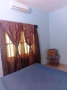 1 dormitorio con 1 cama y una ventana con cortinas en Appartement en location, en Lomé