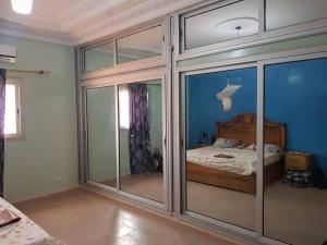 een slaapkamer met een bed en enkele glazen deuren bij Maison meublée a thies. in Thiès