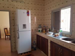 een keuken met een witte koelkast en een wastafel bij Maison meublée a thies. in Thiès