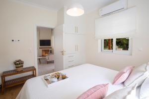 a white bedroom with a bed with pink pillows at Villa Kallisti - private villa with hot tub, large garden, close to the beach in Ayía Varvára