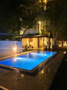 una piscina notturna con un edificio sullo sfondo di Villa Araliya a Hikkaduwa