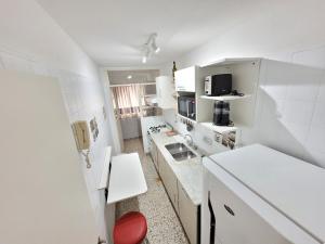 a small kitchen with white cabinets and a red chair at Pampa, Mayo home in Buenos Aires