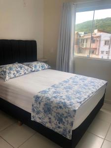 1 dormitorio con 1 cama con manta azul y blanca en Comodidade e simplicidades a 240m do mar, en Florianópolis