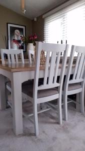 a wooden table with four white chairs around it at Brittany's in Gisburn
