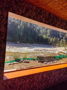 a painting of a river with a forest in the background at Circle Square in Kasol
