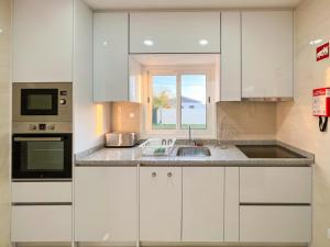 eine weiße Küche mit Spüle und Fenster in der Unterkunft Maison Familiale - Torreira in Torreira