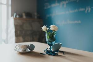 un jarrón con flores blancas y una taza sobre una mesa en Zilais Zirgs, en Skrīveri