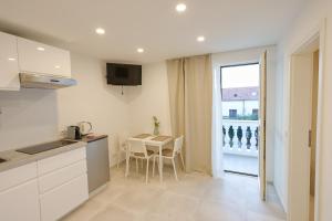 uma cozinha branca com uma mesa e uma janela em Apartment R A M L J A K "Andrija" em Vodice