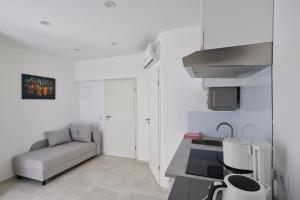 uma pequena cozinha branca com um sofá e um lavatório em Apartment R A M L J A K "Andrija" em Vodice