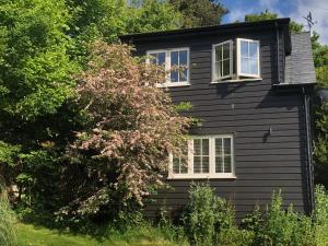 a black house with two windows and a tree at The Nest Danehill in Haywards Heath