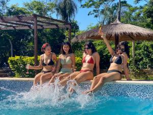 four women in bathing suits sitting in a swimming pool at La Casita de Aregua in Itauguá