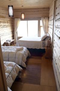 1 dormitorio con 2 camas y ventana en Hotel Boutique Antukenu, en Achao