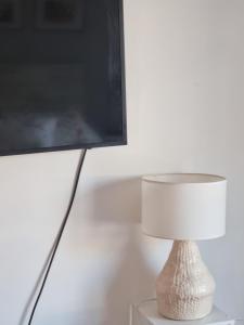 una lámpara blanca sentada en una mesa junto a una TV en salguero suite en Buenos Aires