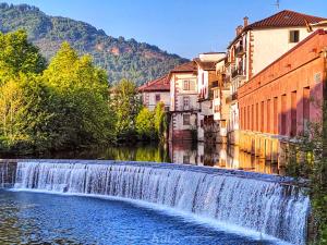 a waterfall in the middle of a river with buildings at Zayas enea in Elizondo