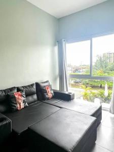 a living room with a black couch and a large window at Modern & convenient condo in Jaco downtown in Jacó