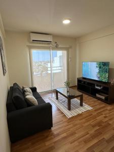 a living room with a black couch and a flat screen tv at Departamento temporal zona Bv Galvez con chochera in Santa Fe