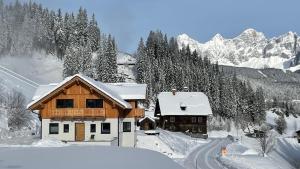 a house is covered in snow with mountains in the background at Haus Tennstein in Schladming