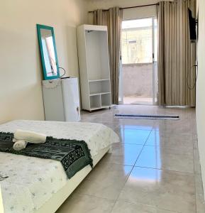a bedroom with a bed and a television on a tile floor at Pousada Piscinas Naturais in Porto De Galinhas