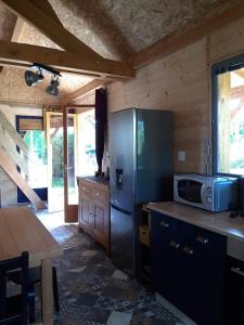 a kitchen with a stainless steel refrigerator and a table at CHALETS POUR FAMILLE ET AMIS in La Chapelle-aux-Chasses