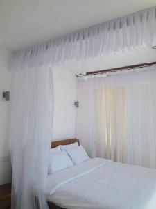 a white canopy bed with white curtains in a bedroom at Entire residential swahili home-Vipingo in Kikambala