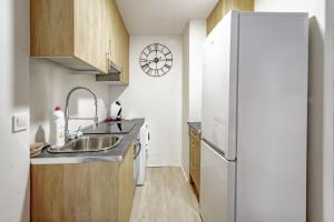 una pequeña cocina con fregadero y nevera. en Apartamentos Hortaleza, en Madrid