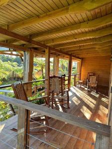 a porch of a wooden cabin with chairs on it at Casa de Paz in Guayama