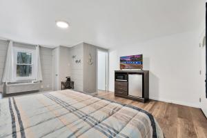 1 dormitorio blanco con 1 cama y TV en The Blue Anchor Unit #1, en Houghton Lake