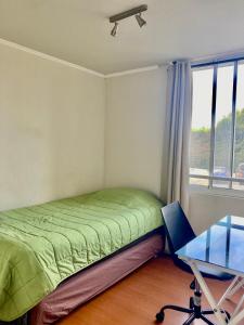 a bedroom with a bed and a desk and a window at Departamento Alto Libertad Meseta Coraceros in Viña del Mar