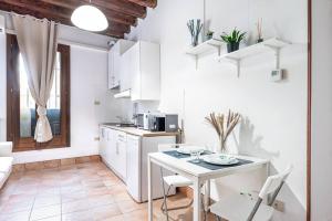 a white kitchen with a white table and a table at Guggenheim House [ Dorsoduro ] in Venice