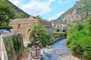 un ponte su un fiume vicino a una montagna di Jolie maison en pierre esprit chalet avec Jacuzzi a Serdinya